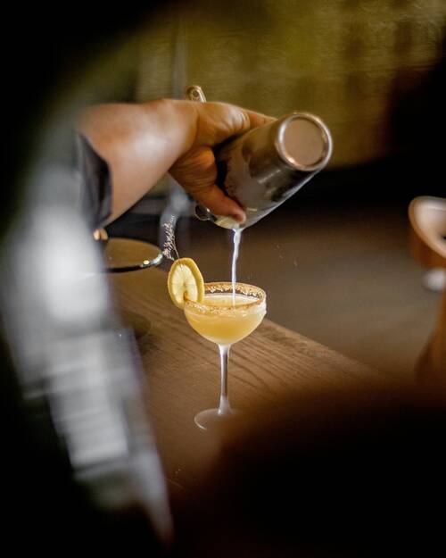 Ein Bartender gießt einen Cocktail in ein Glas.