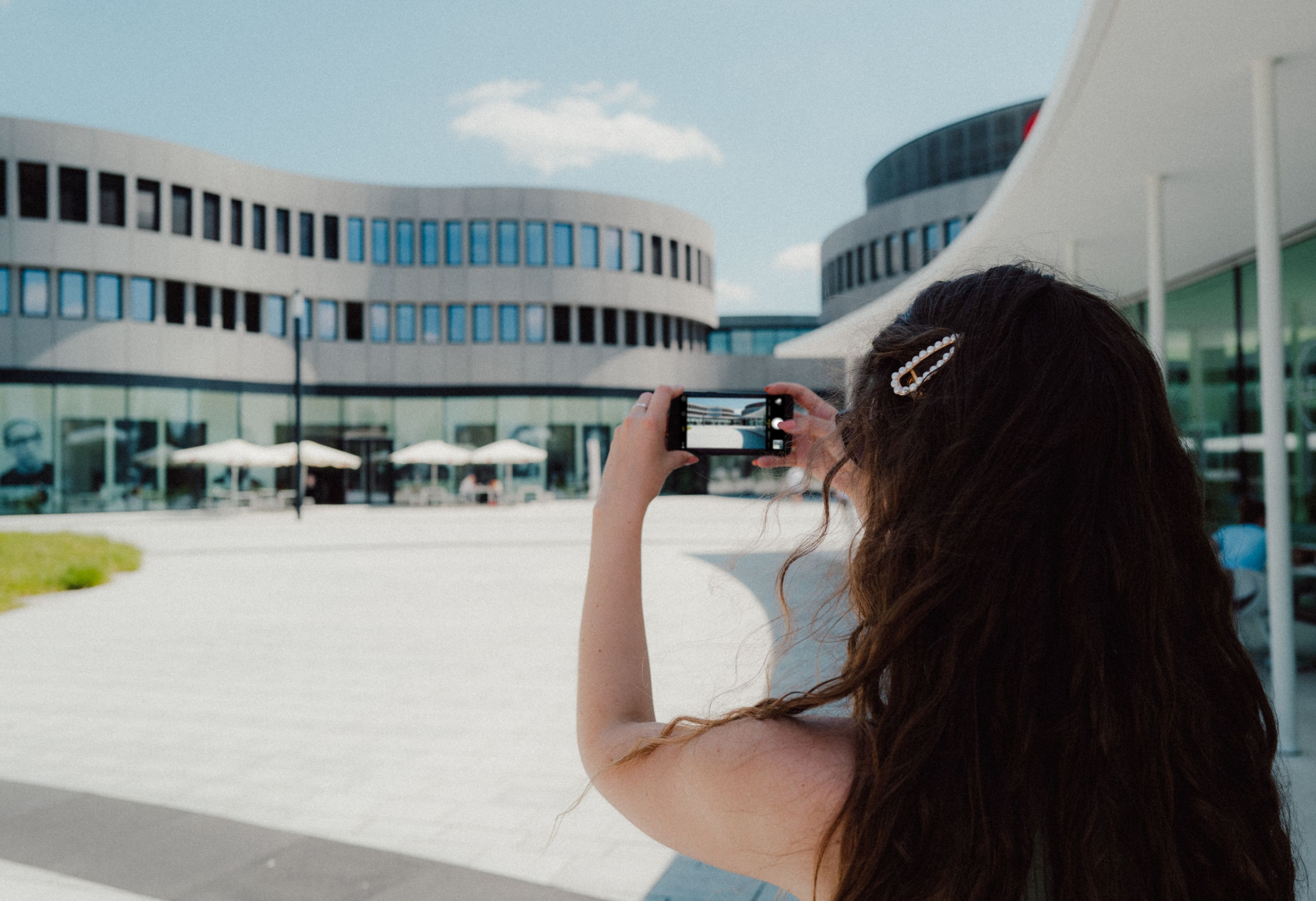 Eine Frau fotografiert mit ihrem Smartphone ein Gebäude im Leitz-Park Wetzlar.