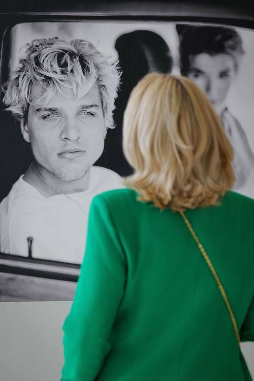 Eine Frau betrachtet das Porträt eines Mannes in der Leica Galerie.