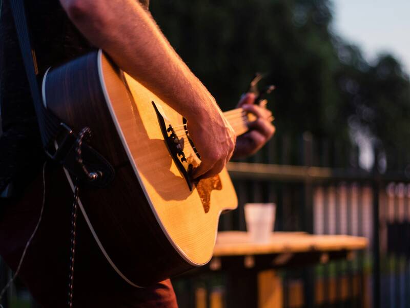Ein Mann spielt Gitarre auf einer Open-Air-Bühne.